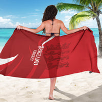 Red England cricket sarong held open, white crest and text details