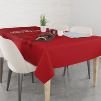 Red cricket-themed tablecloth on dining table with cups and small centerpiece
