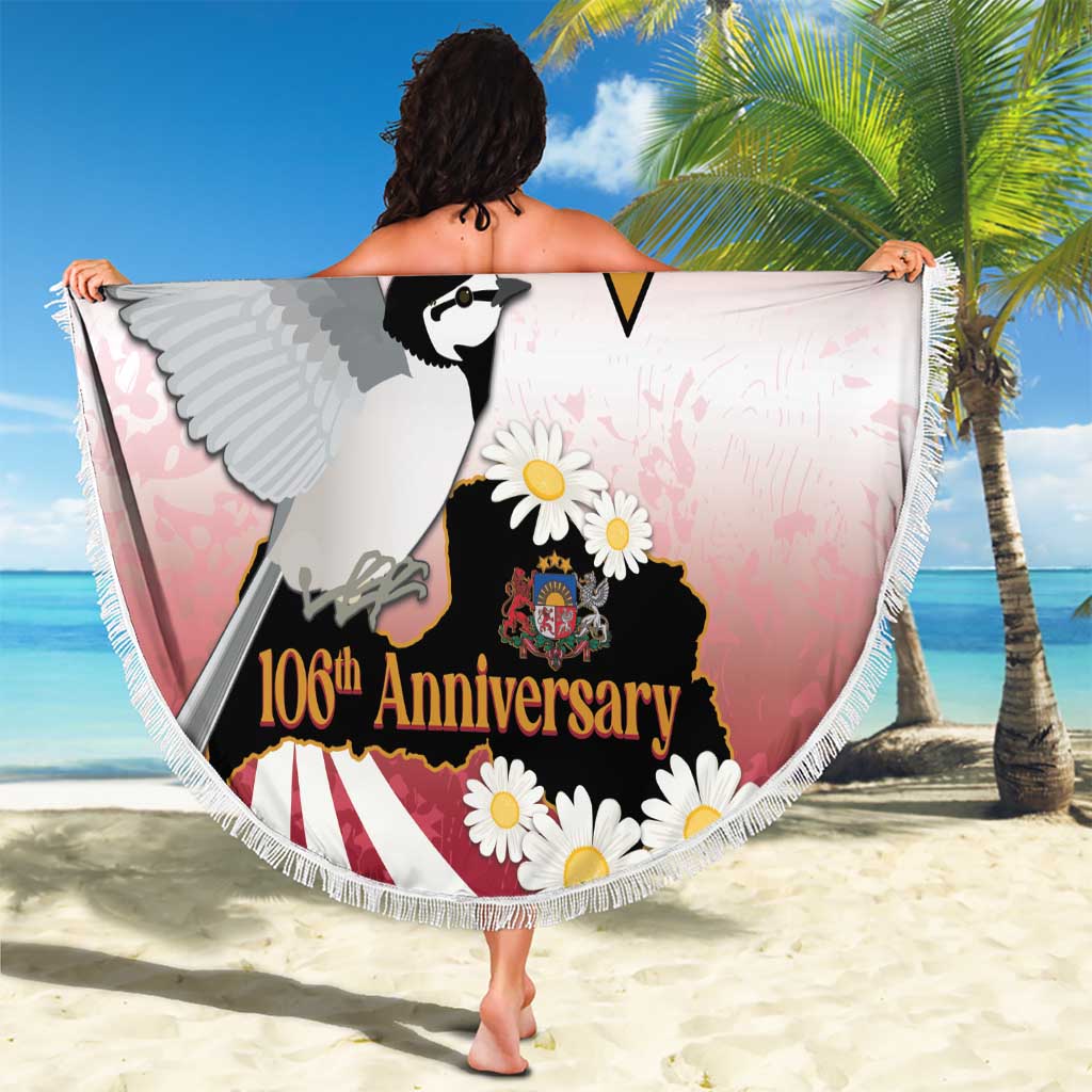 Round Latvia-themed beach blanket held open, bird, flowers, and 106th Anniversary text
