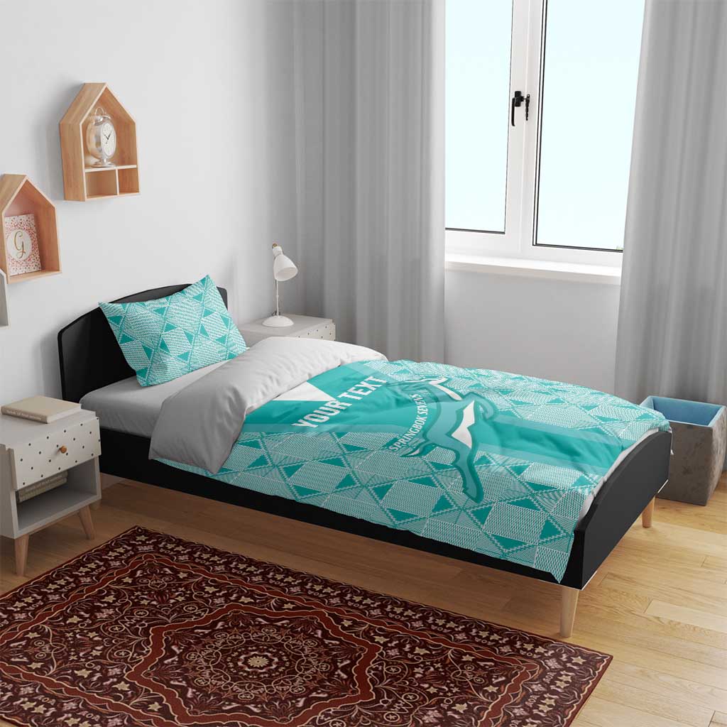 Teal patterned bedding set with duvet and two pillows on a bed with headboard