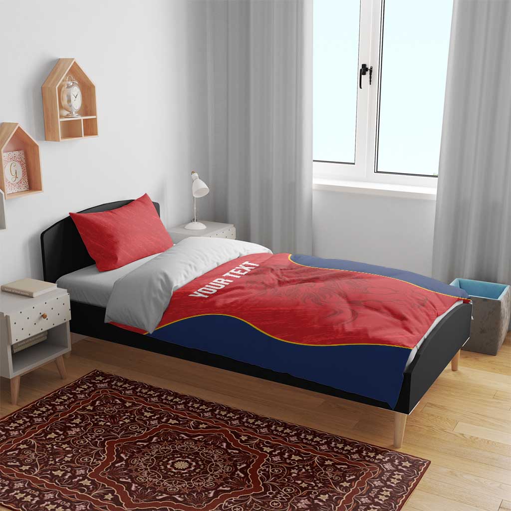 Red and navy bedding set on a bed: duvet with yellow-trimmed design and “YOUR TEXT” center
