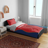 Red and navy bedding set on a bed: duvet with yellow-trimmed design and “YOUR TEXT” center