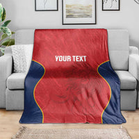 Red Spain rugby blanket on gray sofa, navy sides with yellow piping and “YOUR TEXT”.