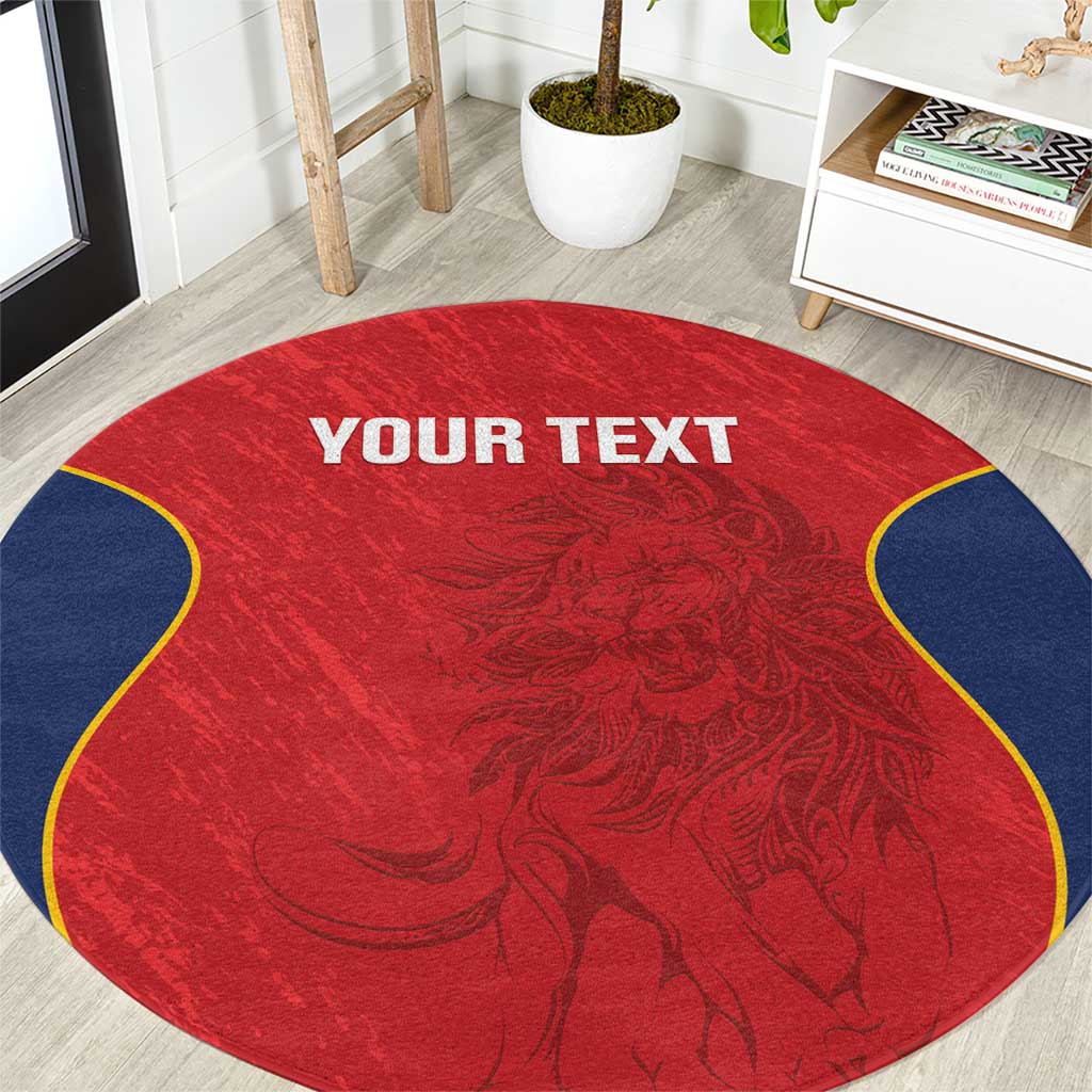 Round red rug with navy scalloped edge, ornate crest pattern, "YOUR TEXT" centered