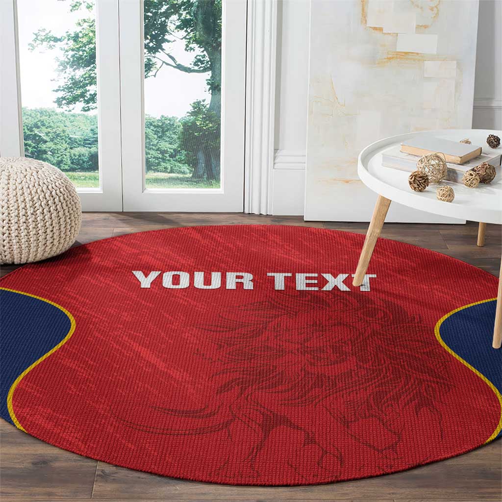 Round red rug with navy-trimmed edge and ornate crest design, "YOUR TEXT" near center