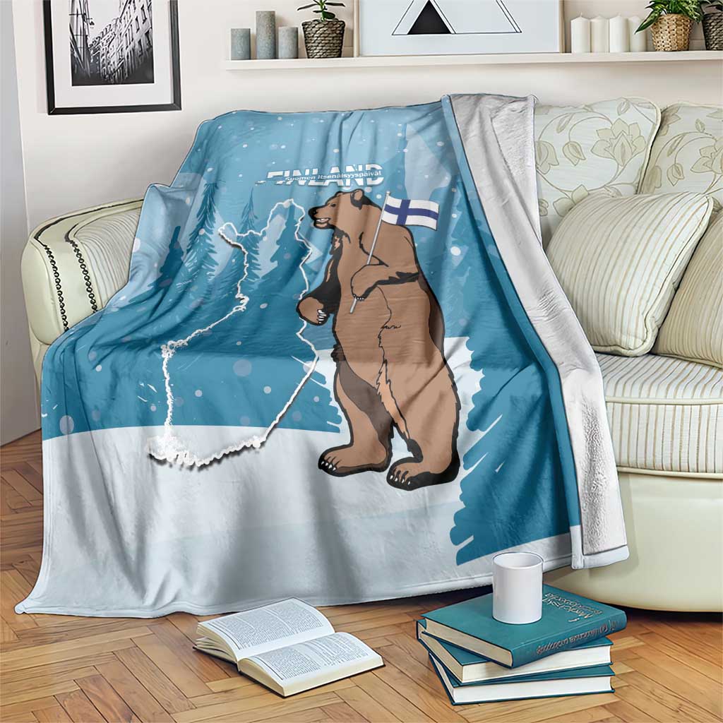 Blue bear and Finland flag throw blanket with map and snowy dots, draped on a sofa