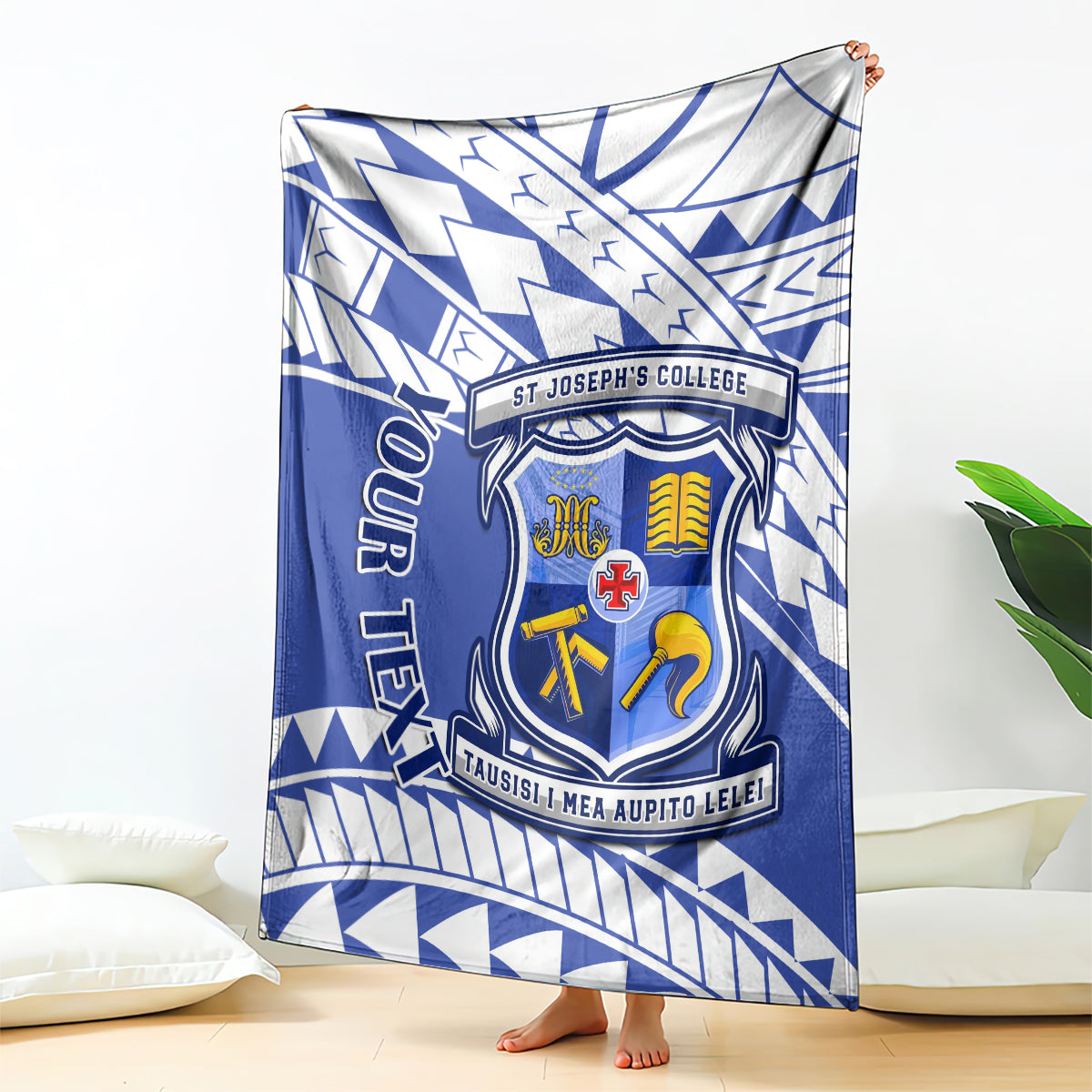 Blue and white St Joseph's College crest blanket with geometric Samoan pattern, draped on bed