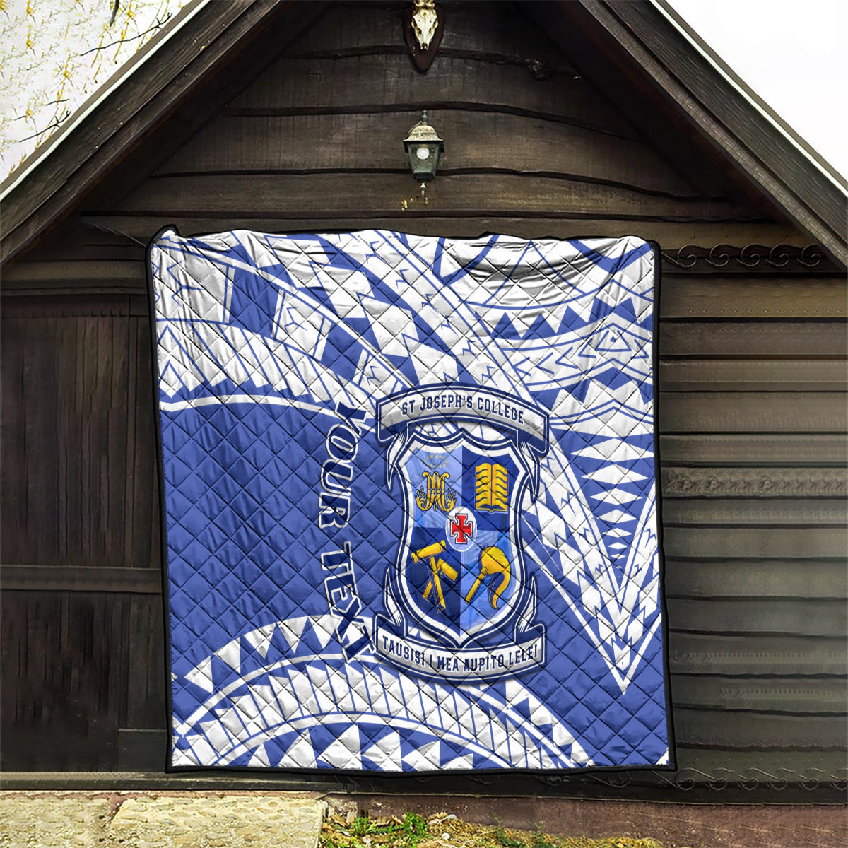 Blue and white quilt with St Joseph’s College crest and geometric pattern displayed