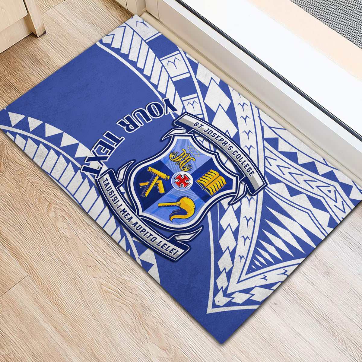 Blue rubber doormat close-up with school crest, white geometric shapes, and “YOUR TEXT”.
