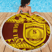 Person using a round fringe beach blanket by pool; gold and maroon crest design