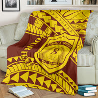 Maroon and gold Polynesian crest blanket spread across a couch
