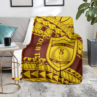 Maroon and gold Polynesian pattern college blanket on a couch arm