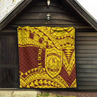 Gold and maroon quilt displayed indoors, quilted geometric pattern with central shield crest
