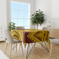 Gold and maroon geometric patterned tablecloth over table with dining chairs