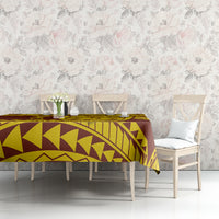 Gold and maroon geometric patterned tablecloth on dining table with floral backdrop