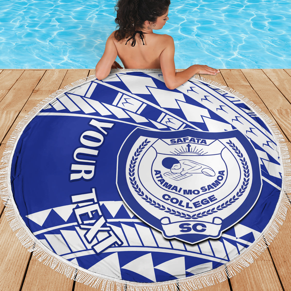 Blue round beach blanket with white fringe and large circular college crest on geometric print