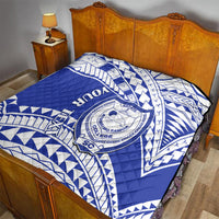 Blue and white quilt with Samoan crest emblem on bed, featuring bold geometric pattern