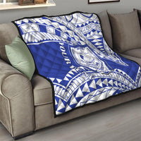 Blue and white geometric Samoan pattern quilt with central crest on sofa