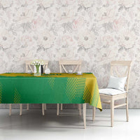 Green and yellow rugby tablecloth on dining table with chairs against floral wall