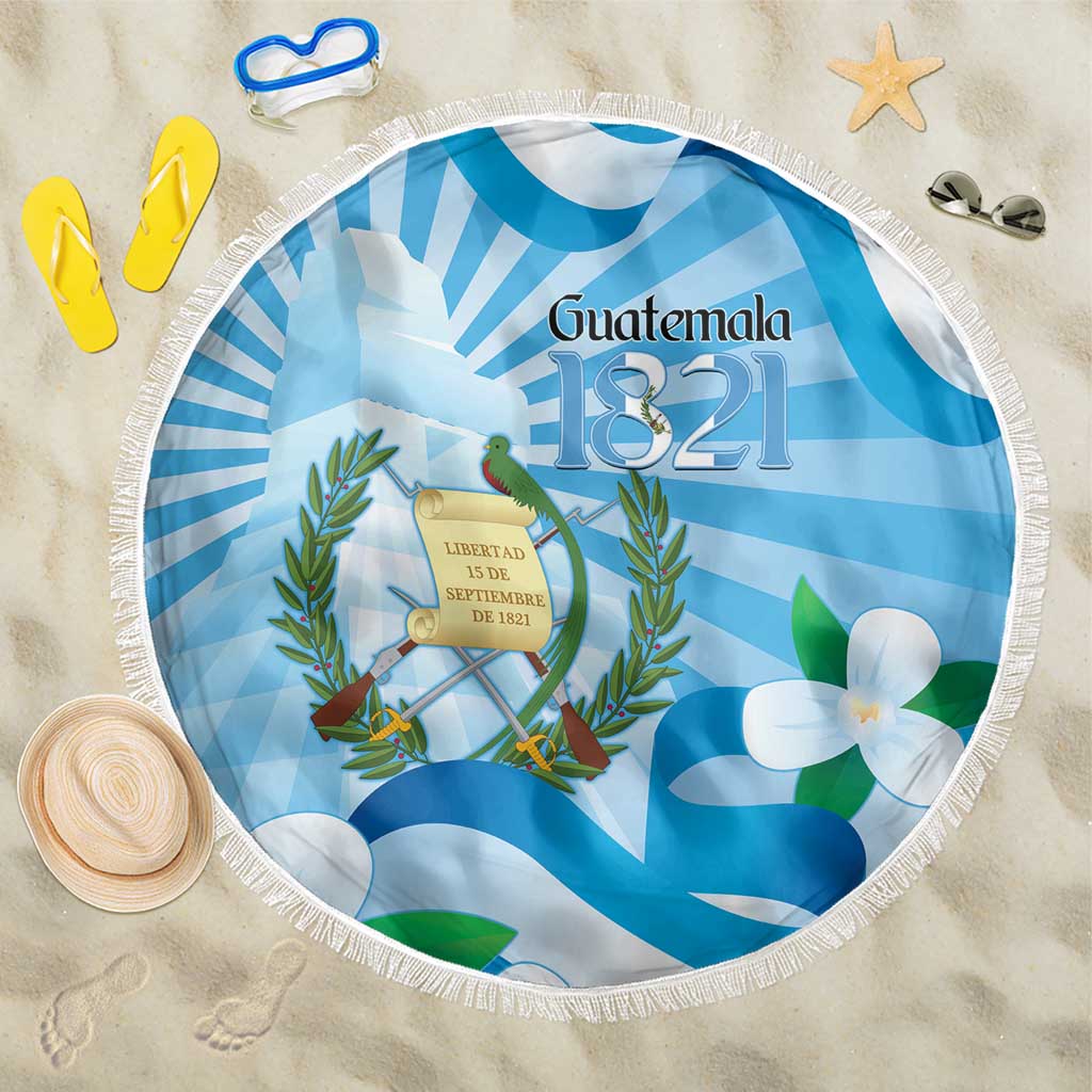 Round blue Guatemala beach blanket with central coat of arms and white flower details