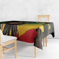 Black tablecloth with bold yellow, green, and red reggae artwork, hanging over table edge