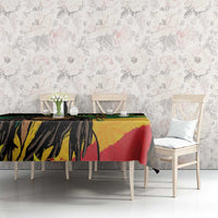 Black tablecloth with colorful reggae face artwork on dining table, styled with chairs