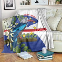 White and blue patterned fleece blanket with bird and flag graphic, draped on a sofa