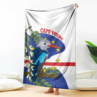 White blanket with blue flag graphic and bird, hanging over the edge of a bed