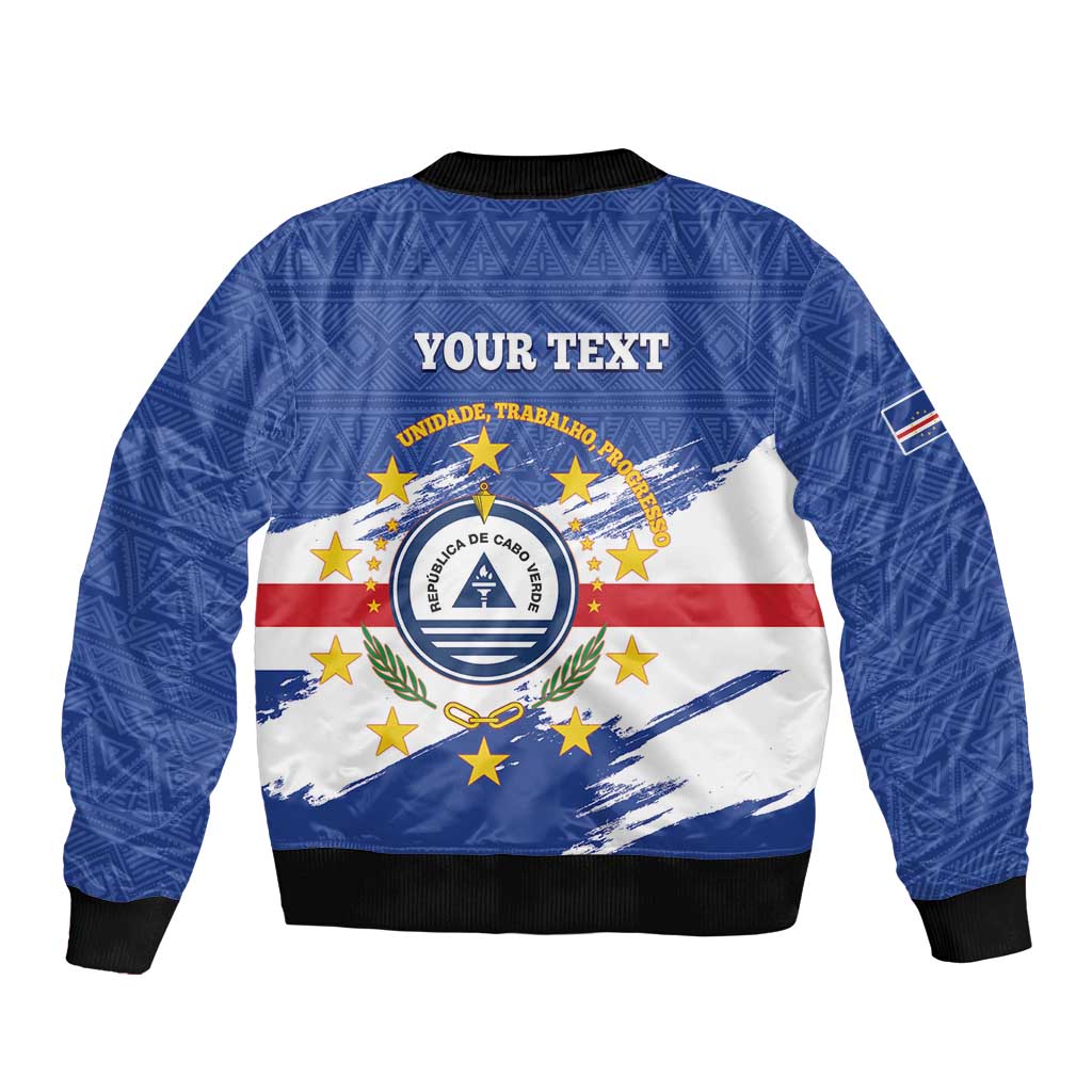 Blue bomber jacket with 'YOUR TEXT' back, Cabo Verde crest over flag graphic, black hem