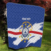 Quilted blanket with blue, white/red stripes, circular crest emblem, 'YOUR TEXT'.
