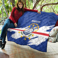 Quilted blanket draped over sofa with blue flag design, stripes, crest, 'YOUR TEXT'.
