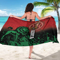 Red and green sarong draped by beach model, featuring large lion graphic and crest