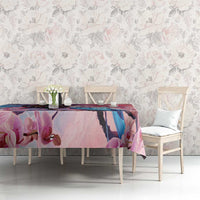Pink floral tablecloth with orchids and coat of arms style crest on dining table