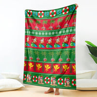 Green Christmas blanket with red panels, palm trees, candy canes, and Santa figures