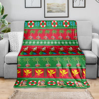 Green holiday blanket draped over a sofa, featuring Santa, palm trees, and garland stripes