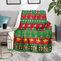 Green Christmas blanket on an armchair seat with palm trees, Santa figures, and red stripes