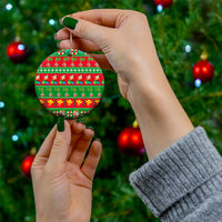 Hand holding a ceramic circle Christmas ornament with red-and-green tropical holiday pattern