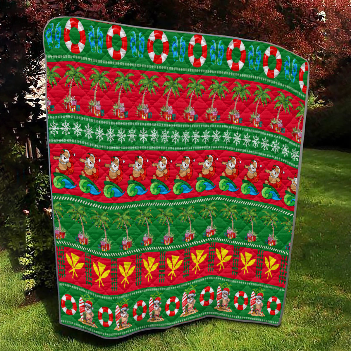 Hawaiian Christmas quilt outdoors, green and red design with palm trees, waves, ornaments, and Santa
