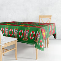 Green Christmas tablecloth draped over bench with Santa, candy cane and star motifs