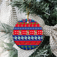 Round ceramic Christmas ornament on tree branch, red and blue holiday tropical pattern
