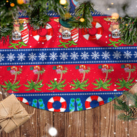 Red and blue circular Christmas tree skirt with tropical pattern, ornaments, and fringe edge