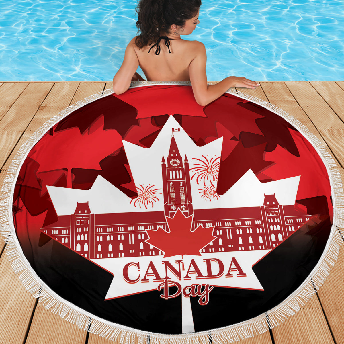 Red round beach blanket with Canada Day lettering, white maple leaf graphic, fringed edge
