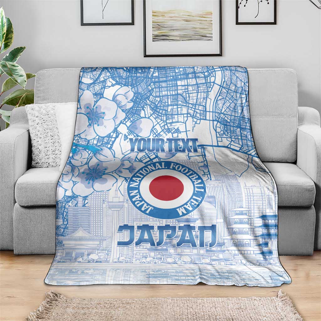 Blue Japan football blanket on a gray sofa, featuring city map and red round logo
