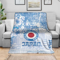 Blue Japan football blanket on a gray sofa, featuring city map and red round logo