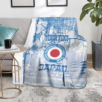 Blue Japan football blanket on the floor with city lines, flowers, and red logo