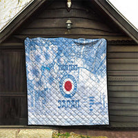 Blue and white quilt hanging display with Japan football logo, city map pattern, and blossoms