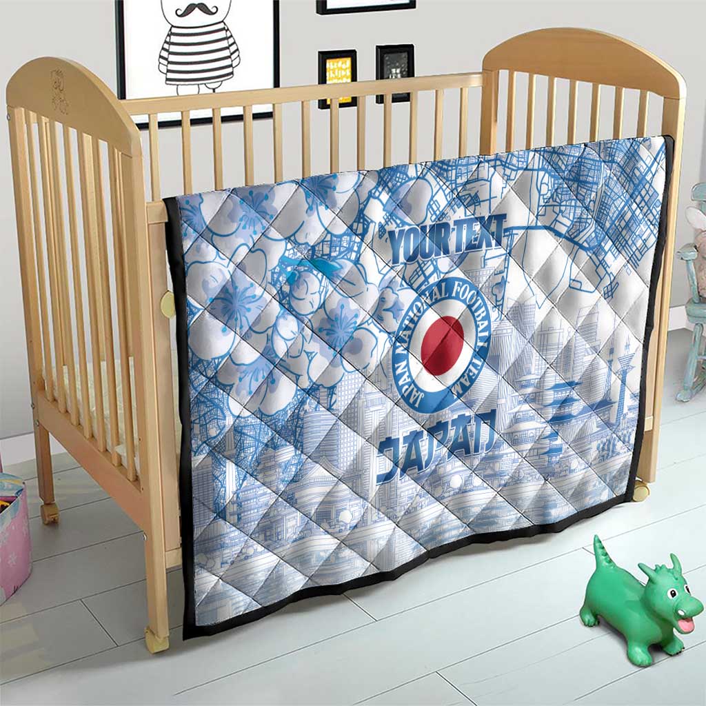 Blue and white quilt laid in a crib with Japan football logo and cherry blossom city design