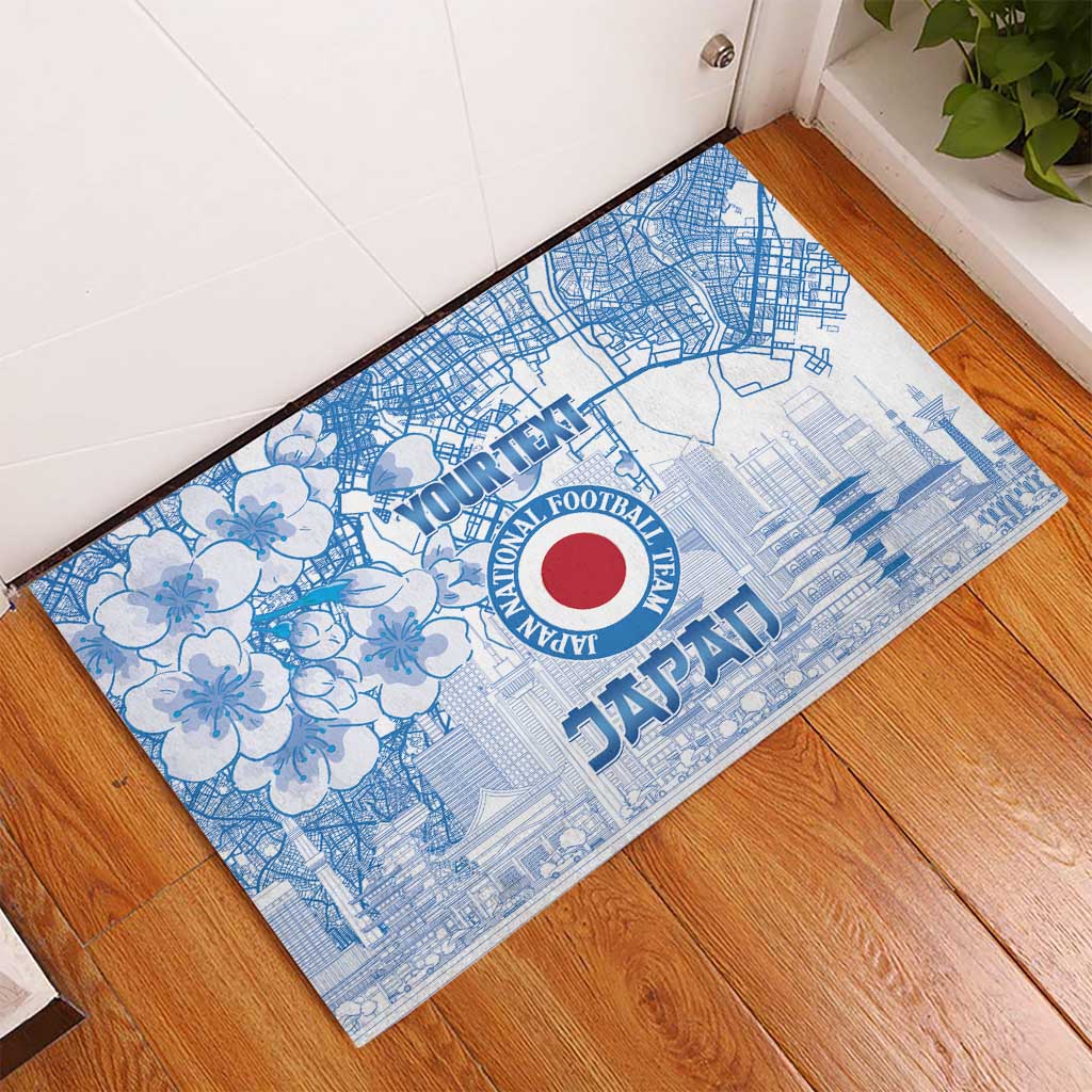 Blue rubber doormat on wood floor with floral pattern, city lines, and Japan crest