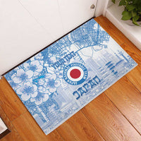 Blue rubber doormat on wood floor with floral pattern, city lines, and Japan crest