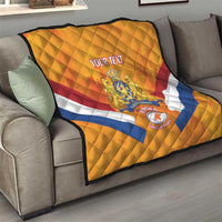 Orange Netherlands rugby quilt on sofa, with quilted diamonds, stripes, and crest